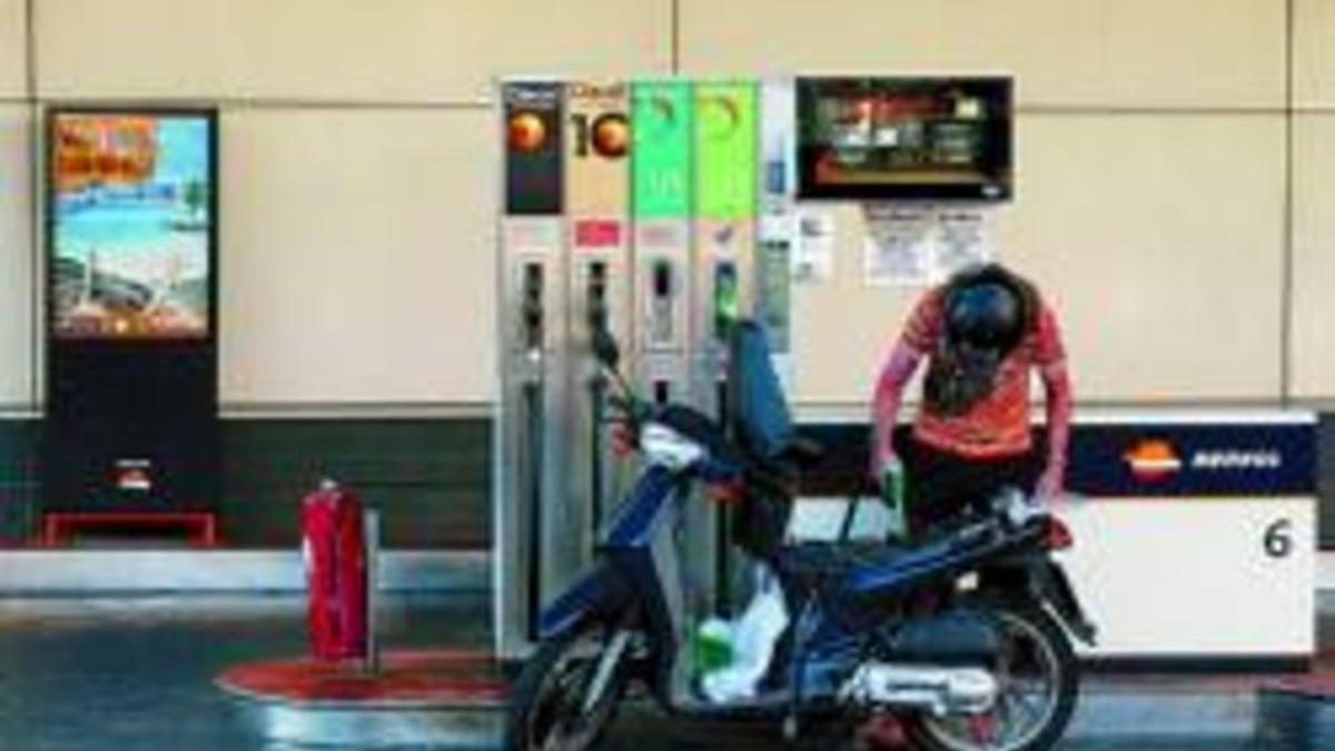 Una ciudadana llena el depósito de su motocicleta en una gasolinera de Barcelona.
