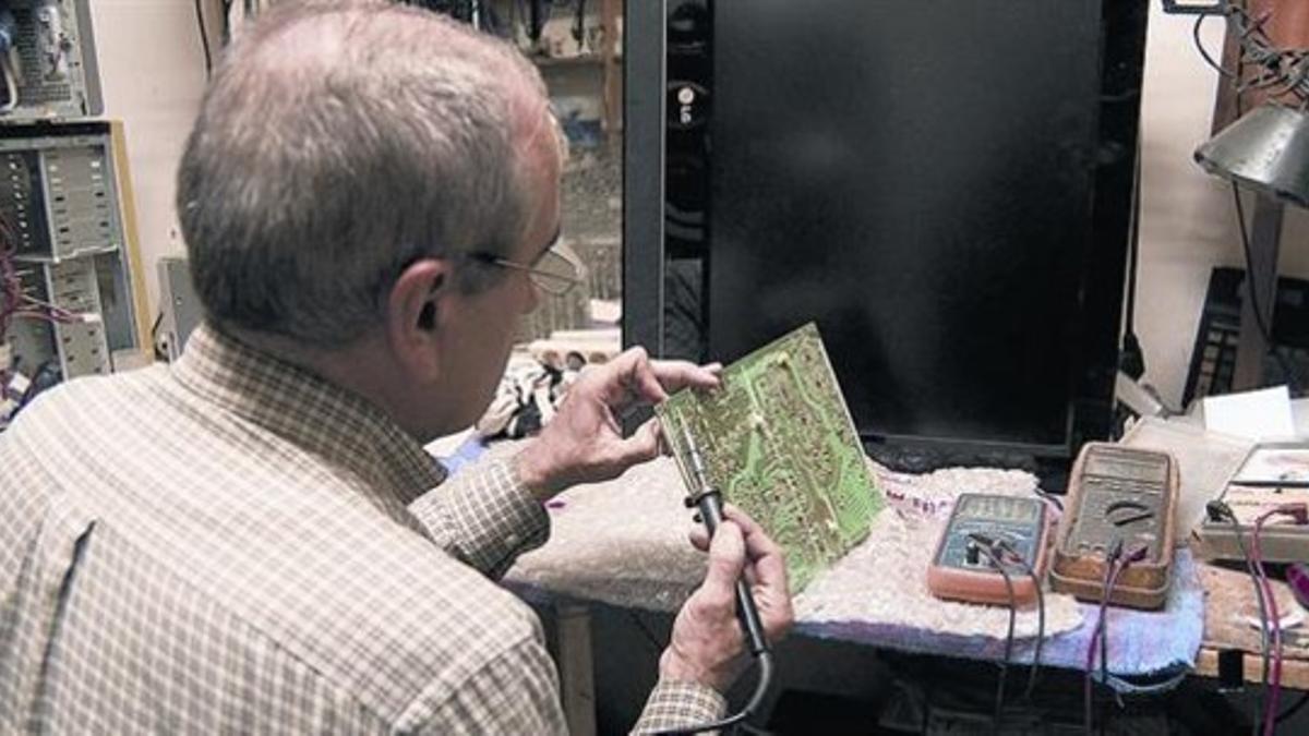 Un técnico realiza una reparación de un componente electrónico en un taller de Gràcia.