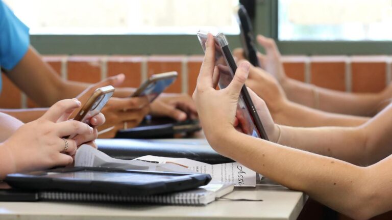 Varios niños consultan sus teléfonos móviles.