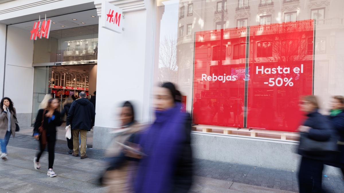 Archivo - Varias personas caminan frente a una tienda de H&amp;M