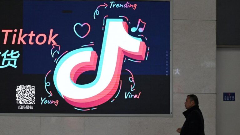 Un hombre pasa delante de un cartel con el logo de TikTok en la estación de tren de la localidad de  Zhengzhou, en China.