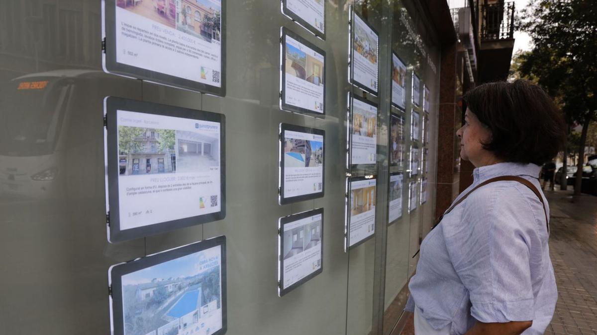 Una mujer mira anuncios de pisos en venta de una inmobiliaria en Barcelona.