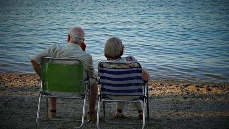 Una pareja de jubilados descansa en la playa.