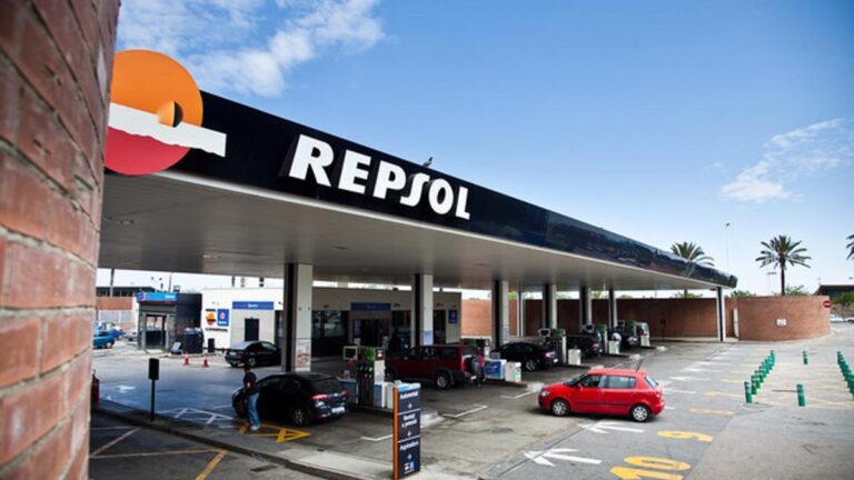 Varios vehículos esperan en una gasolinera.