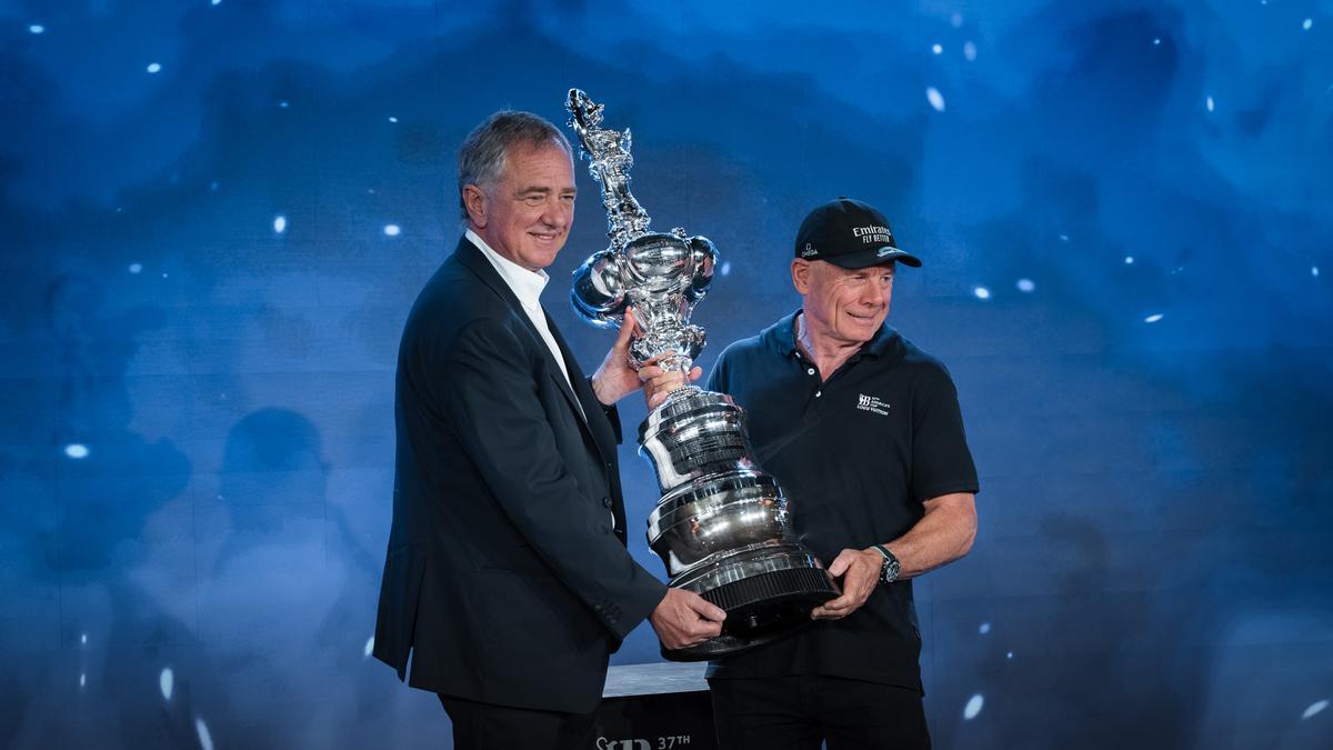 El presidente ejecutivo de la División de Cruceros del Grupo MSC, Pierfrancesco Vago (izquierda), carga la jarra de las cien guineas junto al director ejecutivo de America's Cup Event, Grant Dalton, a bordo del crucero Explora, en Barcelona.)