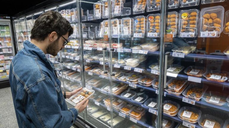 Un consumidor junto a la nevera de comida preparada de un supermercado en Barcelona