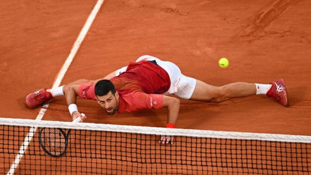 Djokovic devuelve unaa bola desde el suelo.